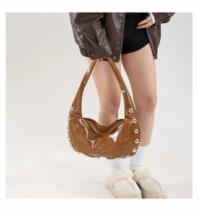Brown oil wax leather crescent bag with silver stud details shown on model in studio