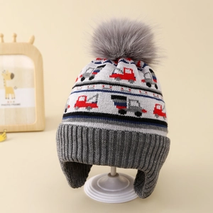 Macro view of warm knit winter hat with excavator pattern and large grey faux fur pompom