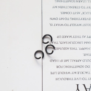Detailed view of three black coated open jump rings for DIY jewelry making on white paper