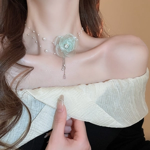 Close-up of elegant light green lace flower necklace with pearls on a female model