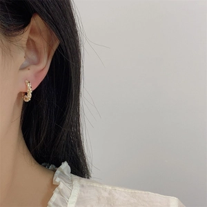 Elegant gold twisted hoop earrings with pearl inlay worn by a model in a side view profile