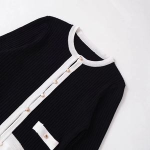 Elegant knit cardigan with black vertical texture and white trim featuring gold buttons