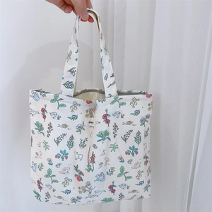 Detailed view of white canvas tote bag with colorful bird and plant illustrations