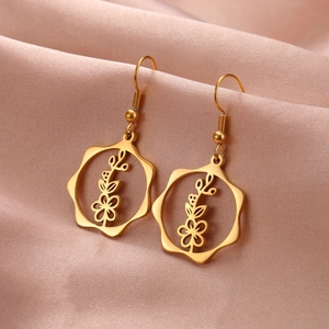 Macro view of gold flower drop earrings featuring intricate cut-out floral patterns