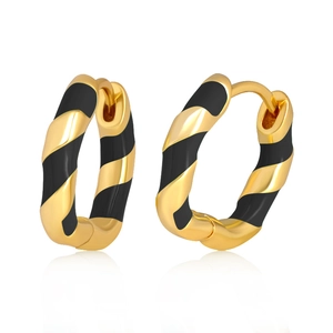 Macro view of gold and black spiral hoop earrings with smooth metal texture and reflections