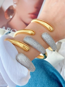 Detail shot of stacked teardrop open bangles with gold finish and pavé cubic zirconia