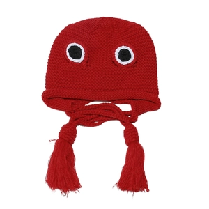 Detail of red knit frog hat featuring large eye accents and thick braided tassels