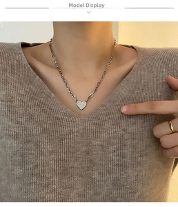 Detail of heart pendant necklace with thick metal link chain on a knit sweater