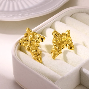 Macro shot of gold-plated petal earrings with irregular metal texture in a gift box