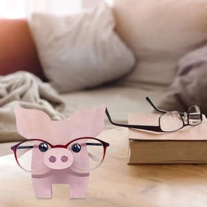 Detail of pink wooden pig glasses holder on desk in a cozy home setting