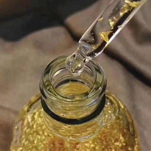 Macro shot of liquid serum with edible gold foil flakes in a glass dropper bottle