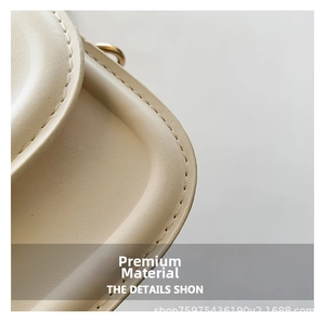 Detailed macro view showing beige leather texture and gold hardware on a small crossbody bag