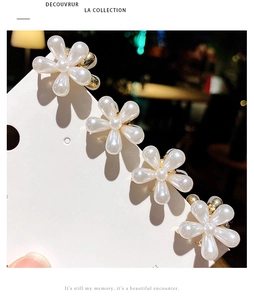 Détail de quatre pinces à cheveux fleurs nacrées à cinq pétales sur un socle doré