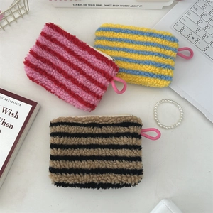 Three striped plush heart coin purses in pink, blue, and brown on a white desk setup