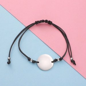 Detail of adjustable black wax rope woven bracelet with polished silver round charm