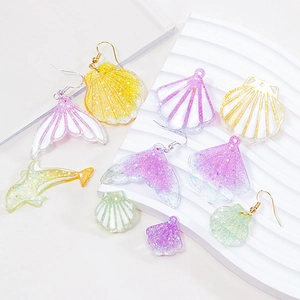 Ocean themed resin earrings and pendants with starfish and shell shapes on a white stand