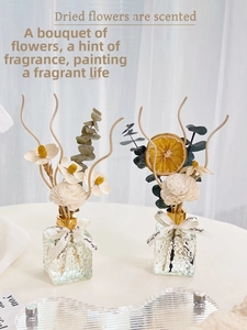 Close-up of reed diffuser with dried eucalyptus, orange slices and sola flowers in glass