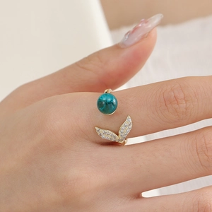 Close-up of golden fishtail ring with turquoise bead and pavé zircon details