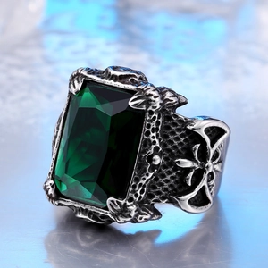 Macro shot of vintage steel ring featuring a large green gemstone and gothic cross patterns