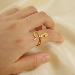 Detail of 18K gold snake ring with fine scale texture worn on finger over satin fabric