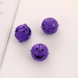 Three purple metal pumpkin bells with cutout jack-o-lantern faces on a white surface