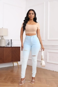 Vue complète d'un jean taille haute déchiré avec un crop top beige porté par un mannequin