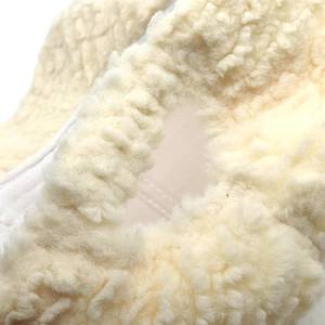 Close-up of white plush baseball cap material showing soft faux shearling texture and stitching