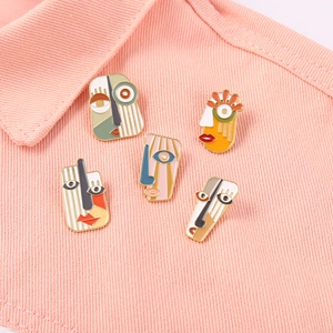 Artistic abstract face enamel brooches set displayed on pink denim fabric material