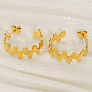 Vue détaillée des boucles d'oreilles dorées ovales irrégulières sur tissu satin blanc