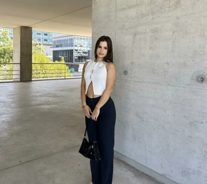 Détail du haut en tricot sans manches blanc boutonné avec un sac à main noir brillant