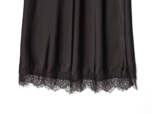 Close-up of black satin skirt hem featuring delicate eyelash lace trim detailing
