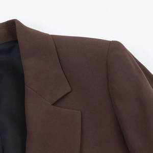 Detail of dark brown blazer featuring notched lapels and shoulder stitching on twill fabric
