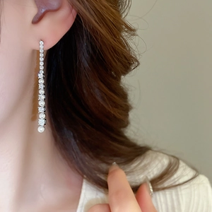 Vue macro de boucles d'oreilles pampilles en argent avec zircons et perles blanches