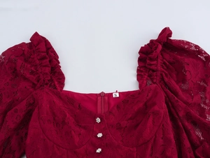Détail de robe en dentelle rouge avec col carré, boutons décoratifs et manches volantées