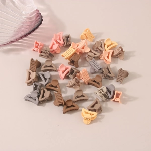 Macro shot of mini matte hair claws in Morandi tones and coffee colors on cream background