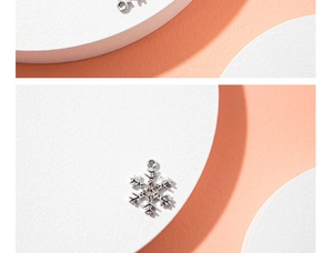 Macro view of silver snowflake pendant with sparkling crystals on a white display stand