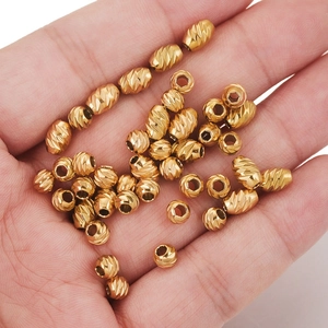 Golden faceted stainless steel wheel beads scattered in a hand for jewelry making