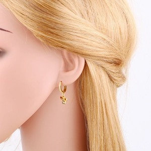 Detail view of gold hoop earrings with crystal-paved insect pendant on a model