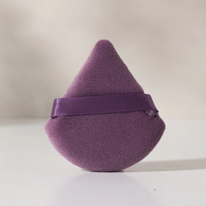 Primer plano de borla de polvos de algodón morado con textura suave y cinta de dedo