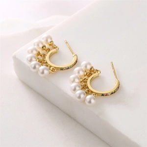 Detail of C-shaped gold earrings with white pearls and multicolored zircon stones