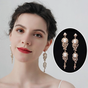 Close-up of elegant gold tassel earrings with pearls and rhinestones on a model