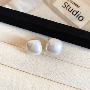 Detail of square pearl stud earrings with a glossy finish inside a jewelry box