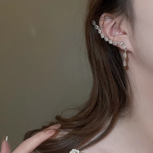 Detailaufnahme einer silbernen Zirkon-Ohrmanschette mit Quasten an einem weiblichen Model