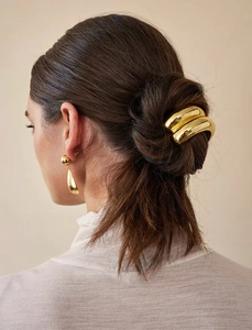 Detail showing golden U-shape hair tie and teardrop earrings on a model hair bun