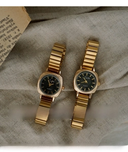 Detail of vintage gold ladies watches with black dial and fluted bezel on old newspaper