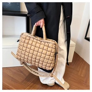Close-up of brown quilted cotton tote bag with thick handles and shoulder strap detail