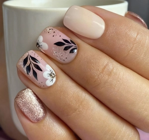 Macro view of nude nails featuring rose gold glitter and floral leaf nail art patterns