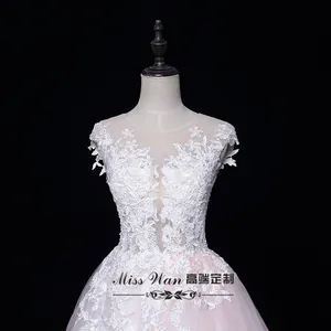 Détail du corsage en dentelle florale blanche avec col en maille transparente et broderie 3D