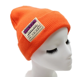 Bright orange knitted beanie with boarding pass patch for autumn winter outdoor wear