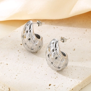 Detailed view of silver teardrop woven stud earrings on a textured stone and silk base